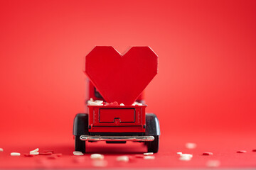 Valentine's day holiday concept. Red toy truck and heart shapes on red background. Place for text.