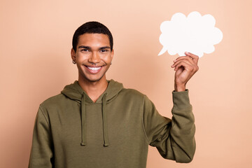Photo of young cheerful satisfied guy wear stylish khaki hoodie hold paper cloud opinion talk...