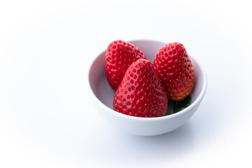 large fresh strawberries inside a bowl on a white background