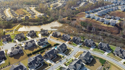 Aerial view urban sprawl and master planning subdivision with row of new development two story houses, lake and nature trail North of Atlanta, Georgia, USA