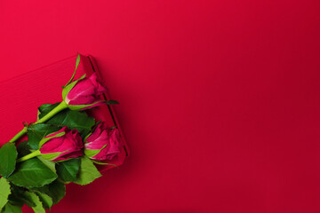 Red roses lie on a red monochromatic background, Valentine's Day