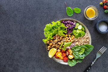 Quinoa, mushrooms, lettuce, red cabbage, spinach, cucumbers, tomatoes, a bowl of Buddha on a dark background. Delicious balanced nutrition concept