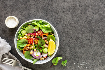 Fresh vegetable salad in a plate on a black background. Top view