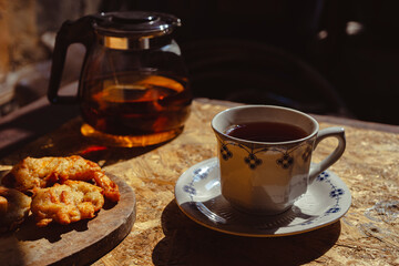 A cup of tea and cookies on dark background, selected focus
