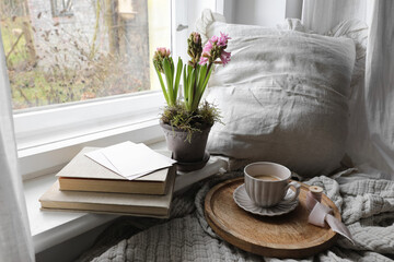 Cozy Easter, spring still life scene. Cup of coffee, books and blank greeting card on windowsill....