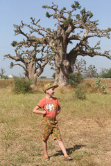 Tourist child, cute boy, fashion kid in Saly, Senegal, Africa. Active recreation, rest, sport. African travel, tourism with kid, child, boy. African nature, baobab