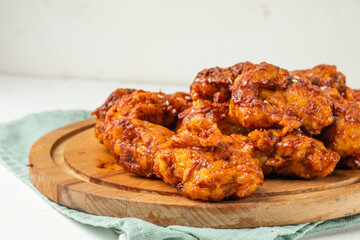 Korean chicken in spicy sauce close-up, deep-fried chicken fillet pieces in red sauce.