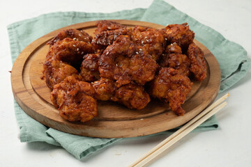 Deep-fried chicken fillet in spices and sauce on a wooden board.