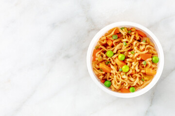 Ramen cup, instant soba noodles in a plastic cup with vegetables, shot from the top with copy space