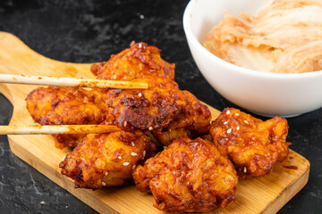 Fried chicken fillet in Korean style is held with chopsticks, close-up, spicy breaded chicken.
