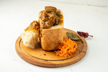 Appetizing curry with meat and vegetables served in white bread, bunny chow. White background....
