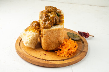 Appetizing curry with meat and vegetables served in white bread, bunny chow. White background. Close-up.