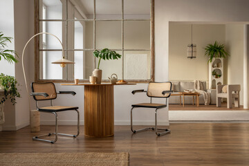 Warm and cozy dining room and living room interior with round table, rattan chair,  pillow, wooden floor, window, beige sofa, stylish armchair and personal accessories. Home decor. Template.