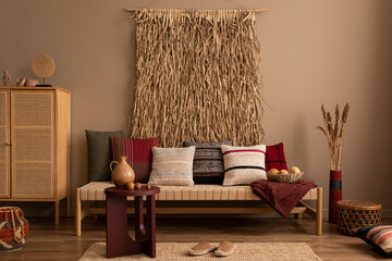 Interior design of ethno living room interior with colorful pillows, rattan sideboard, burgund...
