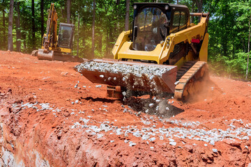 An excavator bucket rakes in crushed stone the excavator is picking up a full bucket of gravel