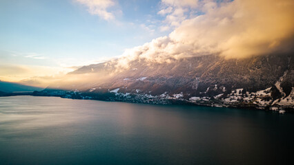 Snow covered mountains around a lake with trees in Switzerland.