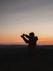 Silhouette of a man photographing the landscape during sunset.