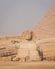The Sphynx with a pyramid in the background in Giza, Cairo, Egypt.