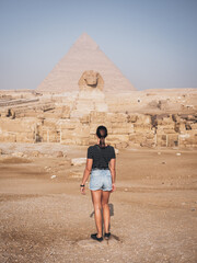 White caucasian young woman standing looking at the Sphynx in Giza, Cairo, Egypt.