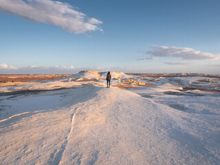 Woman standing on a hillin the landscape in Snow Mountain, White Desert, Egypt.