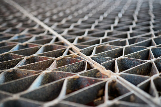 Metal industry steel grade sheet or floor grating with multicolored drops of paint macro closeup. Shallow depth of field diminished perspective industrial grates profiled drainage latticed flooring.