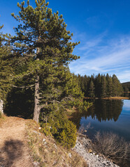 Beautiful view of Black lake, Crno Jezero in Durmitor National Park, Zabljak, northern Montenegro, landscape in a sunny day with blue sky, with glacial lake, forest hiking trail and mountain peaks