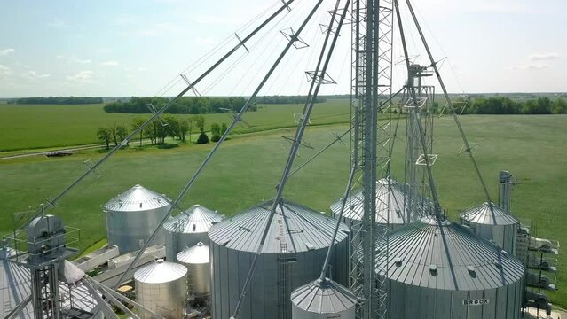 Aerial view rising over industrial metallic grain silo storage processing on Arcadia agricultural farmland, Indiana