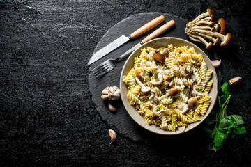 Fusilli paste in plate with mushrooms, garlic and mint leaves.