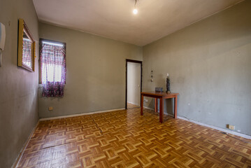 Empty living room with wood-like sintasol floors and a table with objects on it