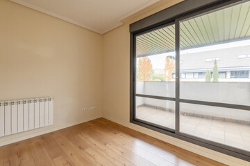 Corner of an empty living room with chestnut flooring and exit to a terrace with anodized aluminum sliding doors leading to a terrace with views
