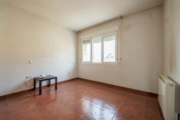 Empty room with two aluminum windows with three panes, red stoneware floors and electric heat accumulator