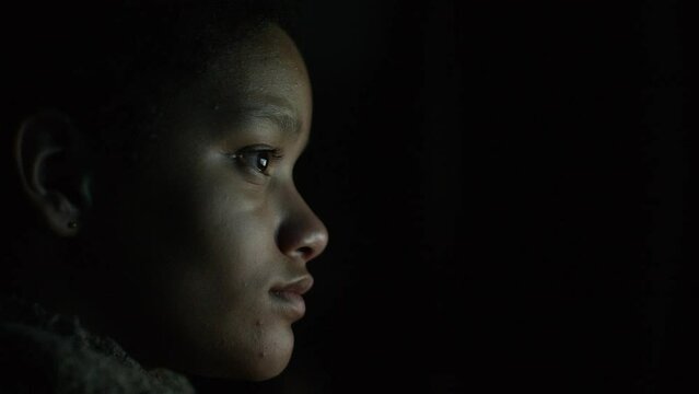 Young female teenager engaged in watching a show on a screen in the dark