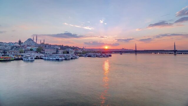 Passenger Ferries near boat station in the Golden Horn near Bosphorus at sunset panoramic timelapse, Istanbul skyline, Turkey. Mosque and bridge on background with reflection on water at sping day
