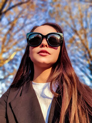 Portrait of a beautiful young woman with smile and sunglasses in the city - 562402203