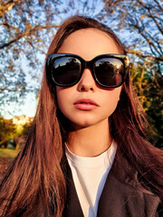 Portrait of a beautiful young woman with smile and sunglasses in the city