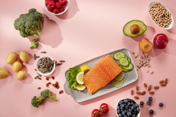 Salmon fillet with various seeds berries and fruits on pink background