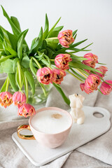 Obraz na płótnie Canvas Cup with cappuccino, spring flowers tulips, morning concept, soy candle, woman's day