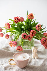 Cup with cappuccino, spring flowers tulips, morning concept, soy candle, woman's day