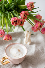 Cup with cappuccino, spring flowers tulips, morning concept, soy candle, woman's day