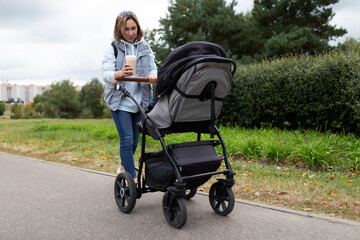 mother with a stroller with a child in the park for a walk