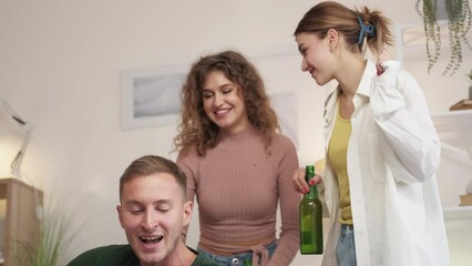 Music party. Happy friends. Home celebration. Joyful women and men feeling good playing guitar singing and dancing in light room interior.