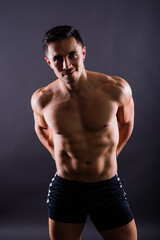 Fototapeta na wymiar Handsome muscular shirtless young man standing confident, front view, looking at camera