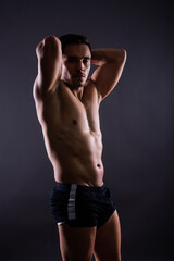 Fototapeta na wymiar Handsome muscular shirtless young man standing confident, front view, looking at camera