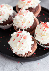 Coffee with muffins, muffins with cream and sprinkles. On a concrete background