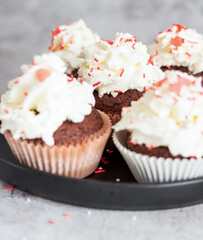 Coffee with muffins, muffins with cream and sprinkles. On a concrete background
