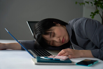 残業でオフィスで居眠りするビジネスウーマン