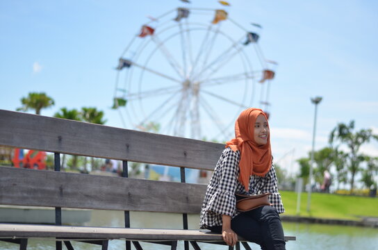 A Woman Is Sitting Behind The Ferris Wheel