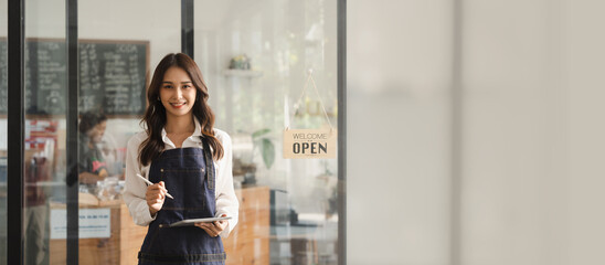 Young asia business owner woman with apron with open sign at café, open again