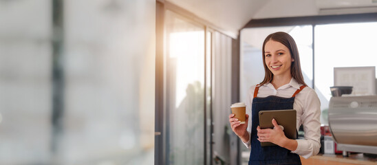 Young friendly female pretty caucasian coffee shop woman owner in apron with open sign, small business owners smiling and service take away orders from food delivery application on tablet.