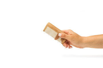 Mano de mujer sosteniendo un peine de madera sobre un fondo blanco liso y aislado. Vista de frente...